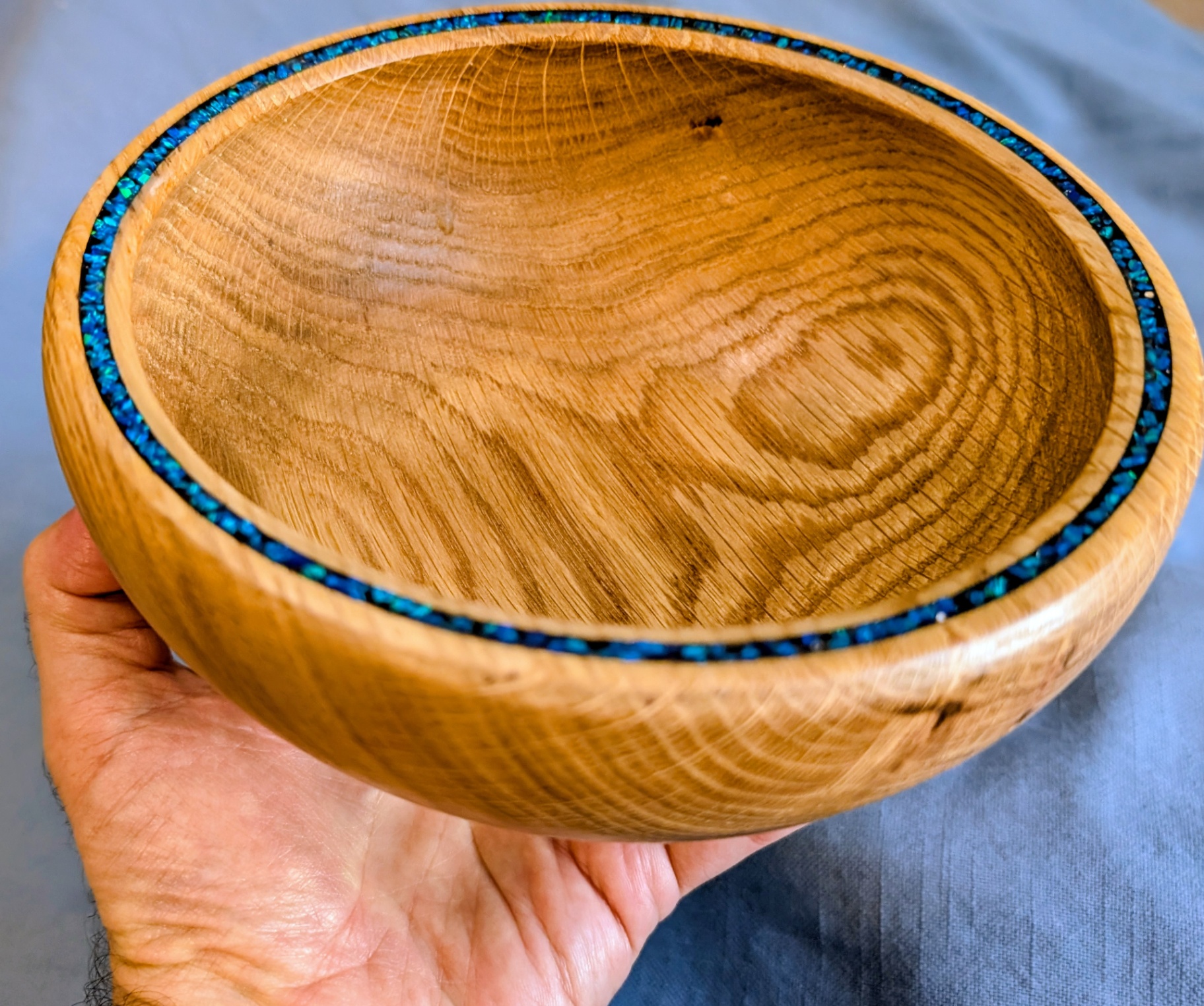 Oak bowl with crushed opal inlay held in hand