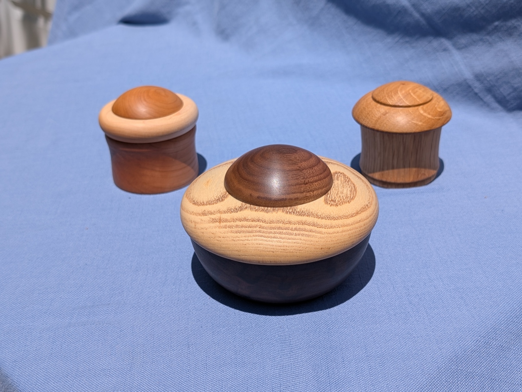 Three small turned lidded boxes in walnut, cherry, and oak with contrasting wood knobs