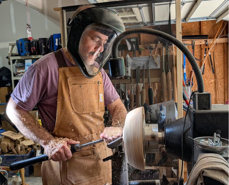 Sam turning a piece on the lathe in the Durham shop